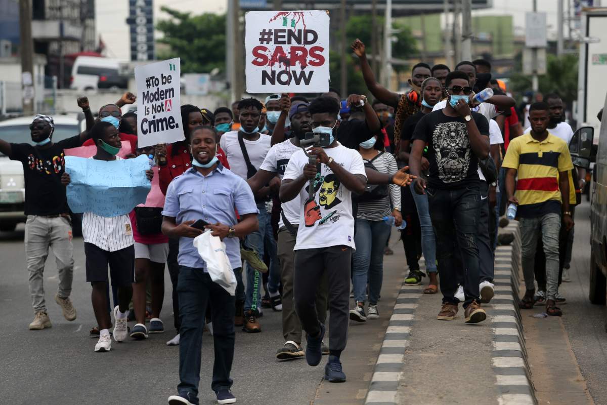 Protesters hold banners as they walk along a road during a protest against the Nigeria rogue police, otherwise know as Special Anti-Robbery Squad (SARS), in Ikeja district of Lagos, Nigeria, Oct. 9, 2020.