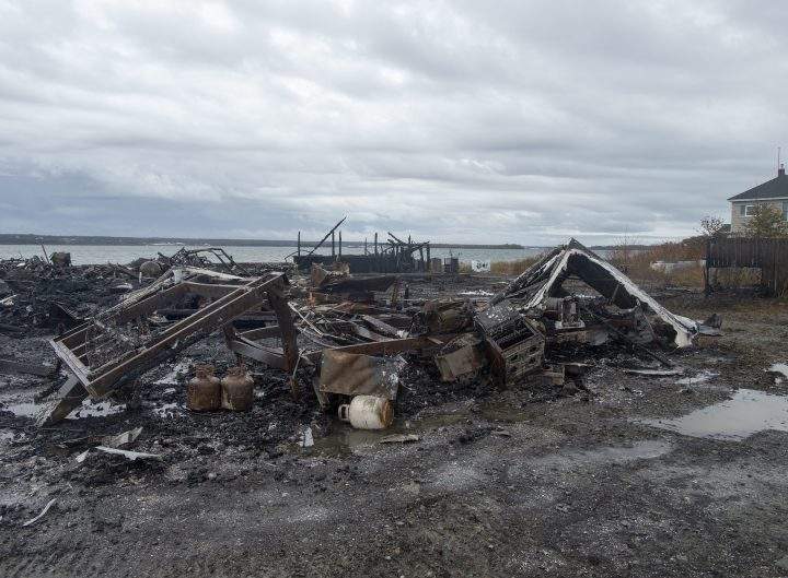 Debris from a burnt-out fish plant is scattered along the shore in Middle West Pubnico, N.S., on Oct. 17, 2020.