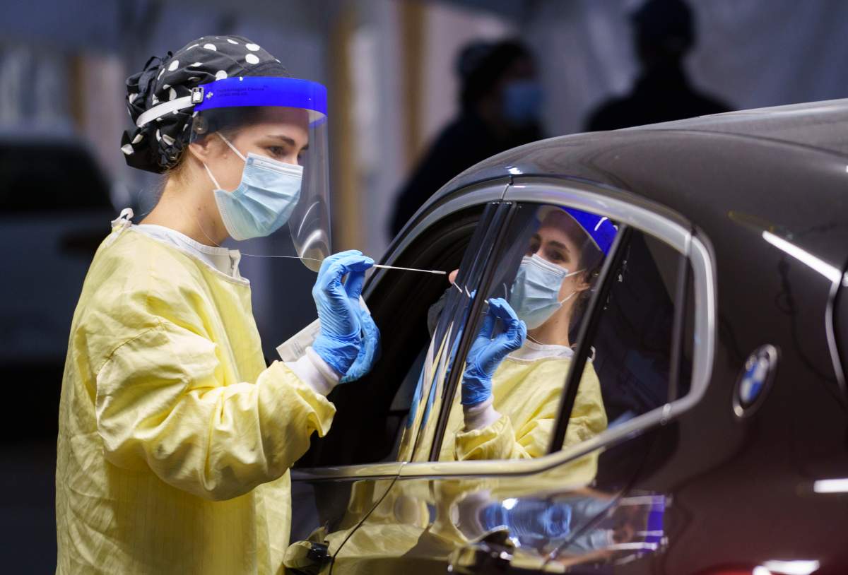 A nurse performs a test on a patient at a drive-in COVID-19 clinic in Montreal, on Wednesday, October 21, 2020. 