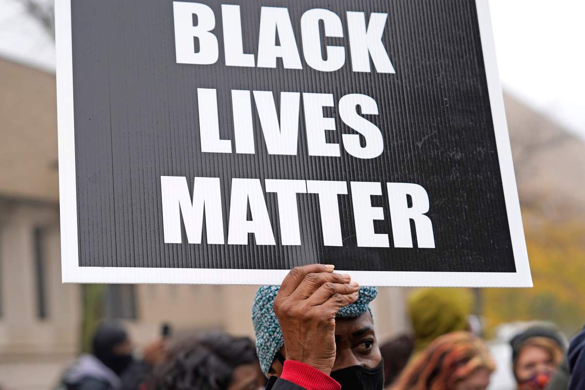 A woman holds a sign during a protest rally for Marcellis Stinnette who was killed by Waukegan Police Tuesday in Waukegan, Ill., Oct. 22, 2020.