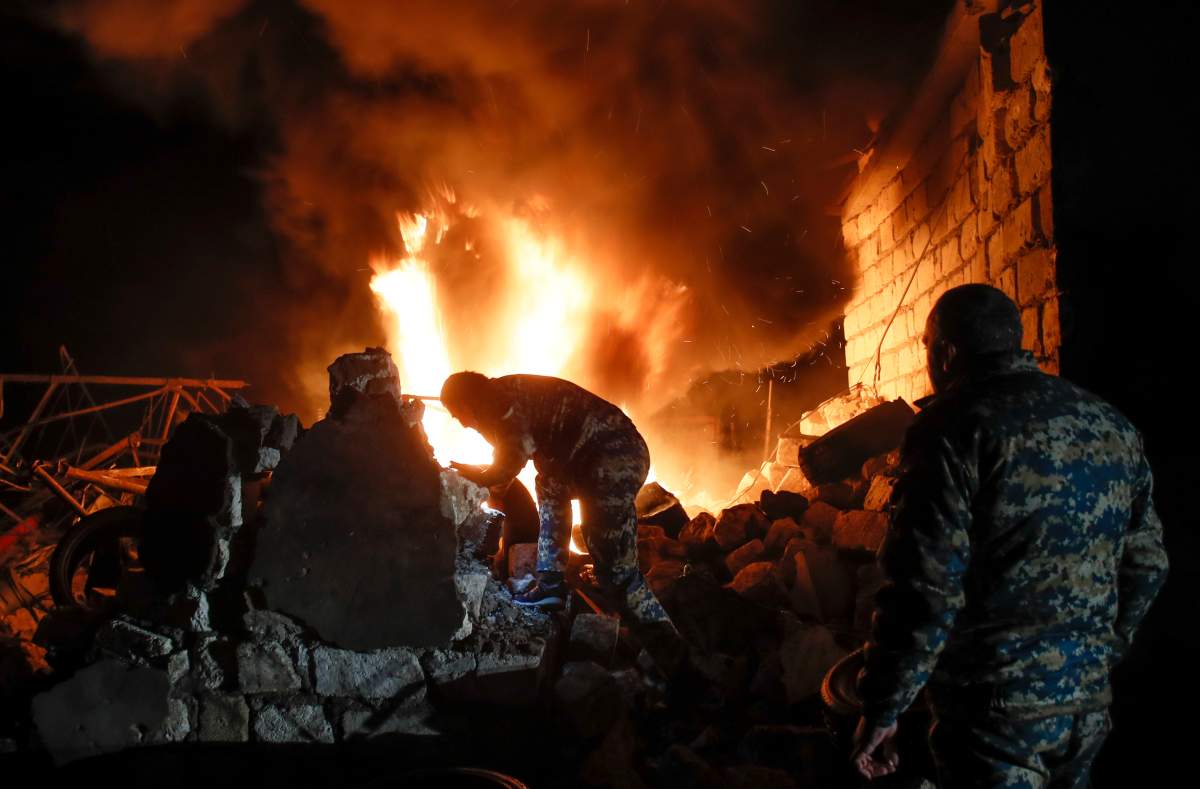 People try to remove car tyres from a car shop on fire after shelling by Azerbaijan’s artillery during a military conflict in Stepanakert, the separatist region of Nagorno-Karabakh, Oct. 23, 2020.