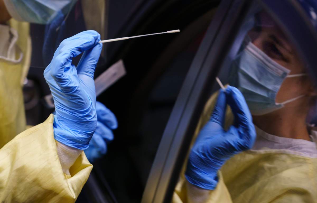 A nurse performs a test on a patient at a drive-in COVID-19 clinic in Montreal, on Wednesday, Oct. 21, 2020.