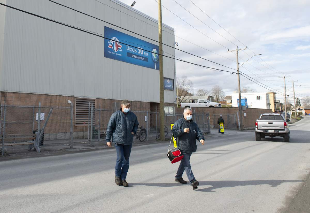 Workers walk outside the Olymel pork processing plant, Thursday, October 29, 2020 in Vallee-Jonction, Que. A COVID-19 outbreak at the plant southeast of Quebec City continues to grow. 