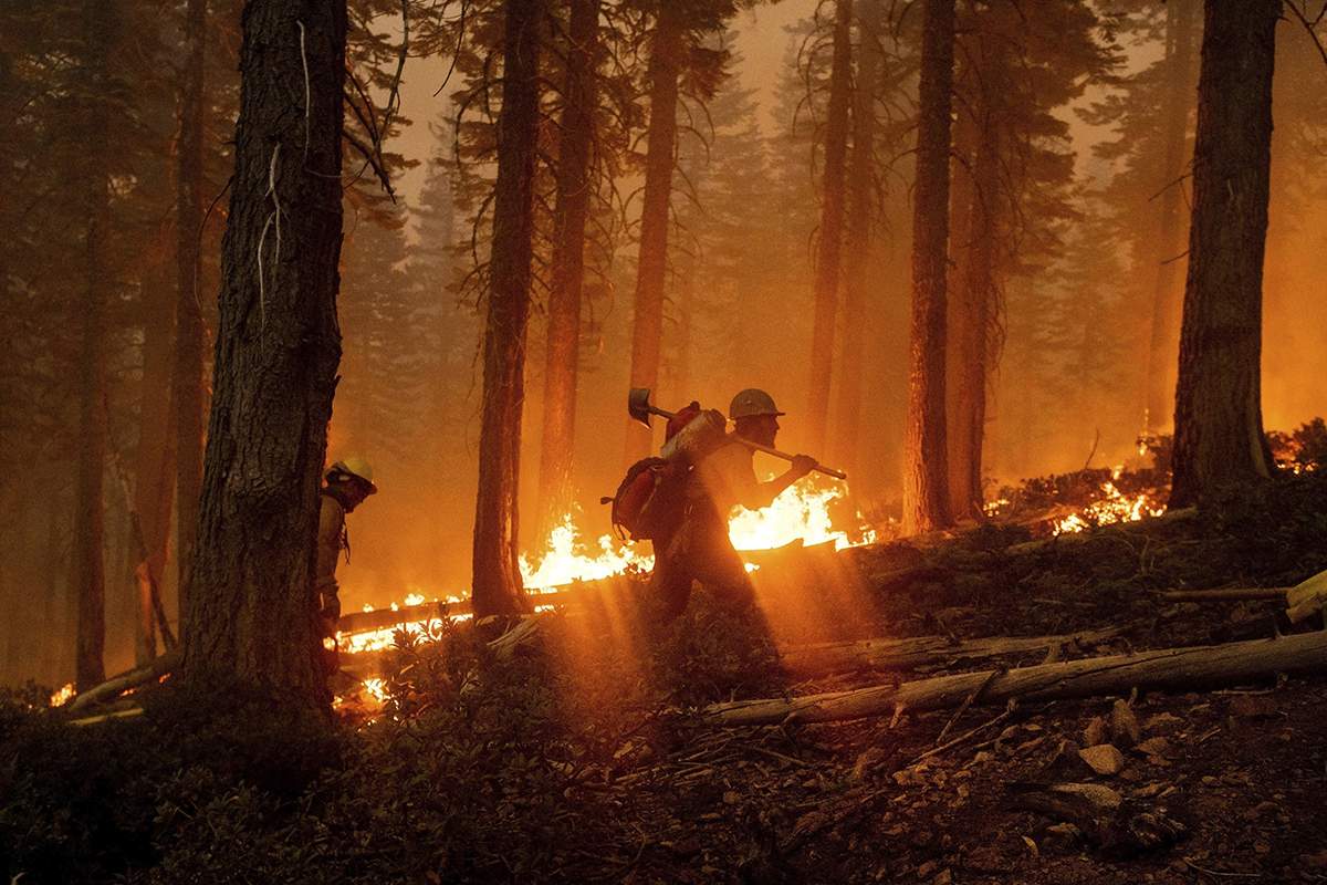 In this Monday, Sept. 14, 2020, file photo, two firefighters can be seen as the  North Complex Fire burns in Plumas National Forest, Calif.