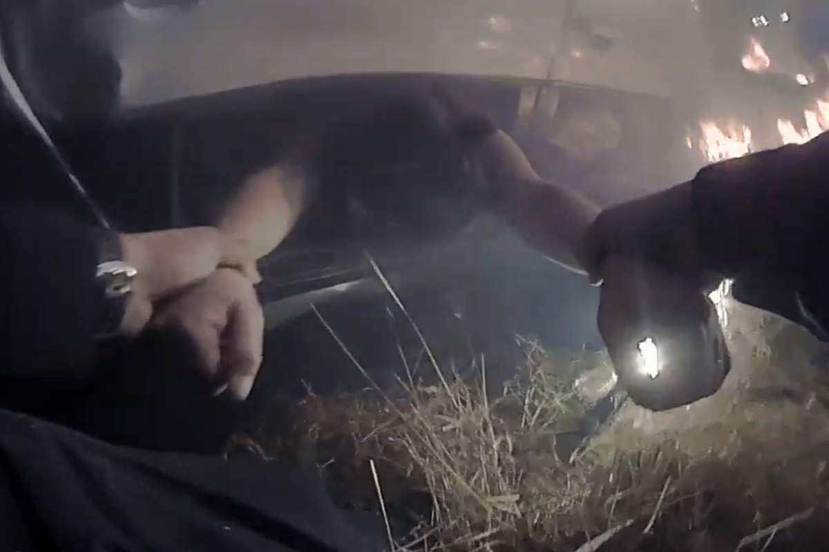 A police officer pulls a woman from a burning car in this image from body-worn camera video on Oct. 17, 2020, near Davis, Calif.