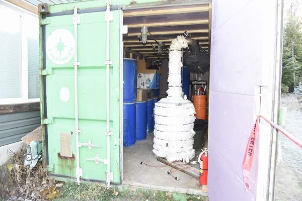 Blue barrels and a distiller inside a shipping container.