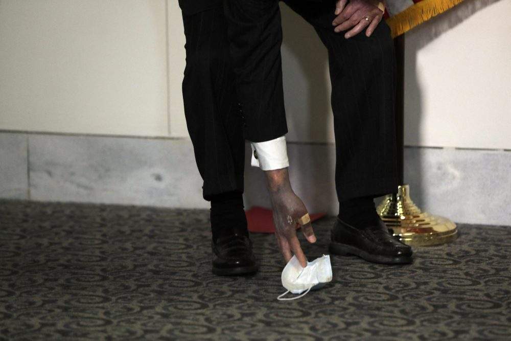 U.S. Senate Majority Leader Mitch McConnell reaches to get a dropped face mask as he talks to the media after the Republican policy luncheon on Capitol Hill in Washington on Oct. 20, 2020.