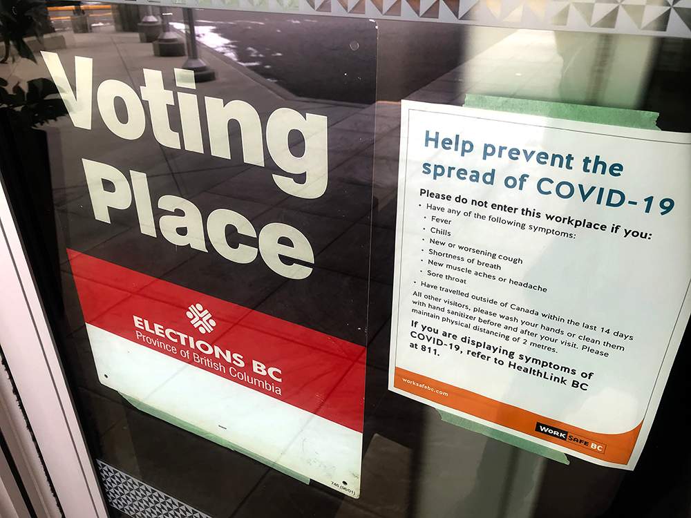 An Elections BC sign alongside a COVID-19 sign during the 2020 general election in B.C., on Oct. 24, 2020.