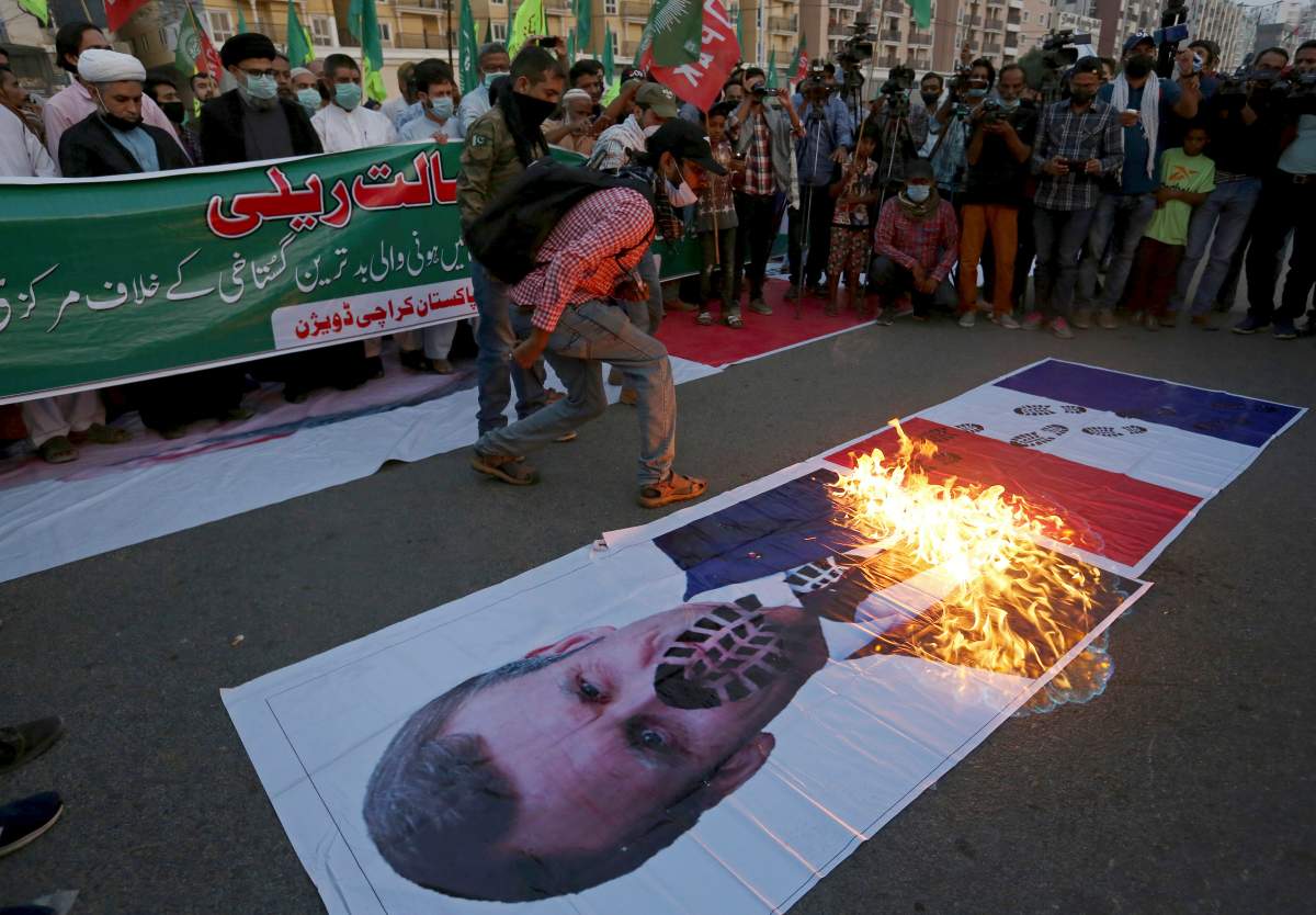 Pakistani Shiite Muslims burn a representation of a French flag and a defaced image of French President Emmanuel Macron during a rally against the French president and the republishing of caricatures of the Prophet Muhammad they deem blasphemous, near the French consulate in Karachi, Pakistan, Nov. 1, 2020. 