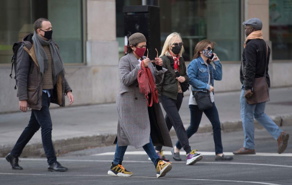 People wear face masks as they walk along a street in Montreal, Saturday, November 7, 2020, as the COVID-19 pandemic continues in Canada and around the world. 