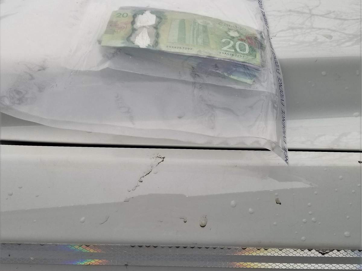 A bundle of cash atop an RCMP vehicle. Kelowna police say the cash was seized from the bank robbery suspect. 