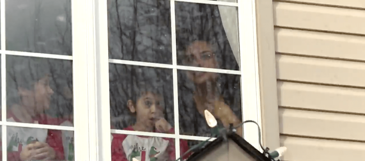 Dominic DaCosta, 5, watches his Santa Claus parade with brother and mother, Denise DaCosta from their upstairs window.