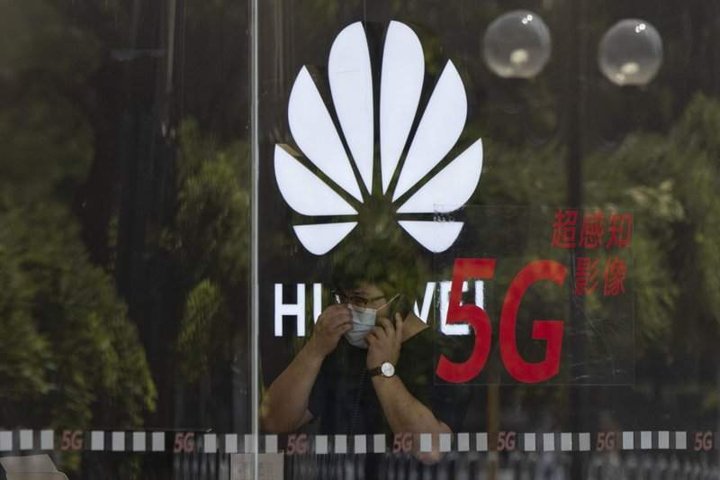 In this Wednesday, July 15, 2020 file photo, a worker wearing a mask to curb the spread of the coronavirus speaks on the phone near the Huawei logo in a store in Beijing. 