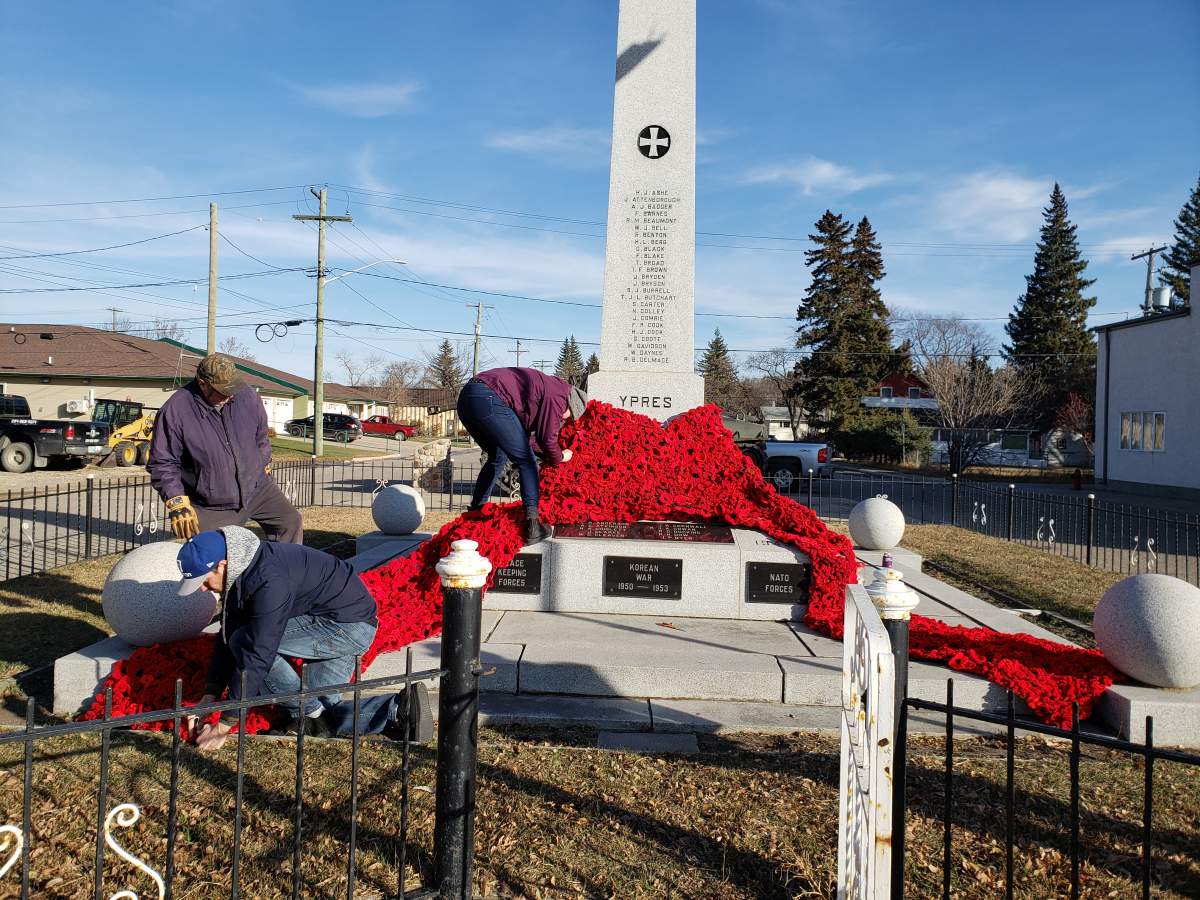 Volunteers position the poppy quilt at Minnedosa’s cenotaph.