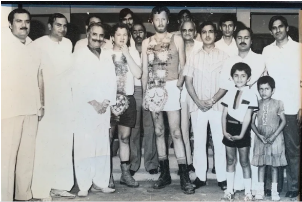 Ken Langley and Garry Sowerby pose for a picture with a family during their travel across Pakistan.