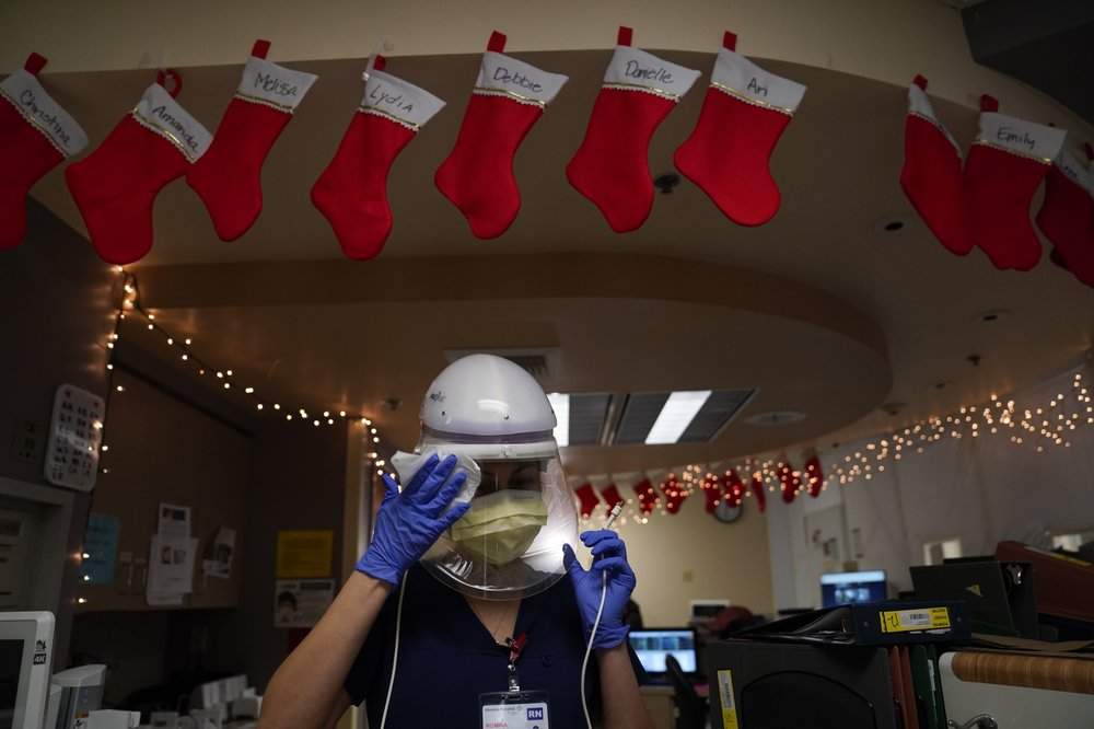 Registered nurse Romina Pacheco disinfects her powered air purifying respirator after tending to a patient in a COVID-19 unit decorated with Christmas stockings with nurses’ names written on them at Mission Hospital in Mission Viejo, Calif., Monday, Dec. 21, 2020.
