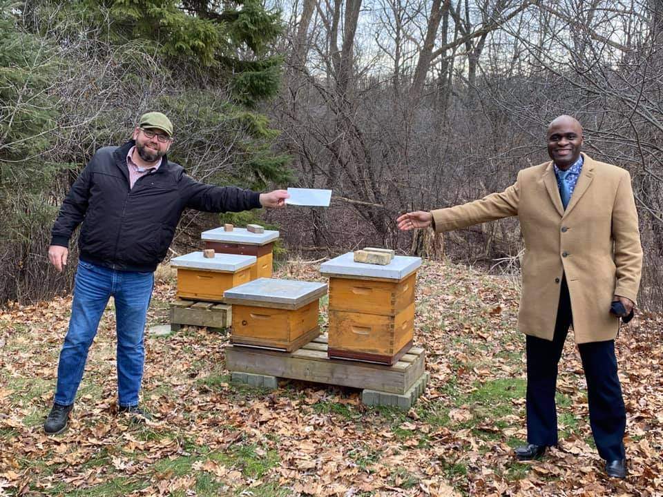Beekeeper Peter Andersen (left) hands over a $7,500 cheque to Leroy Hibbert of LUSO (right).