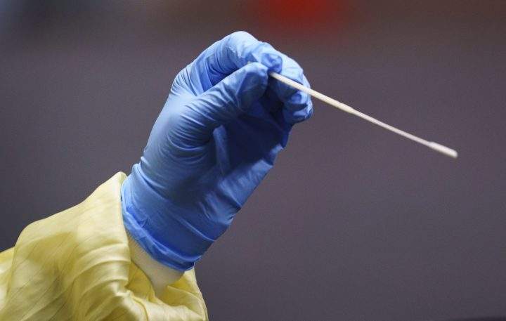 A nurse uses a swab to perform a test on a patient at a COVID-19 clinic in this file photo.