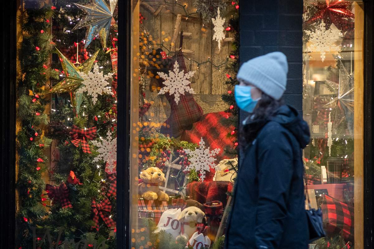 A person wears a disposable mask while walking past Christmas decorations in a store in Kingston, Ontario on Friday, December 4, 2020.