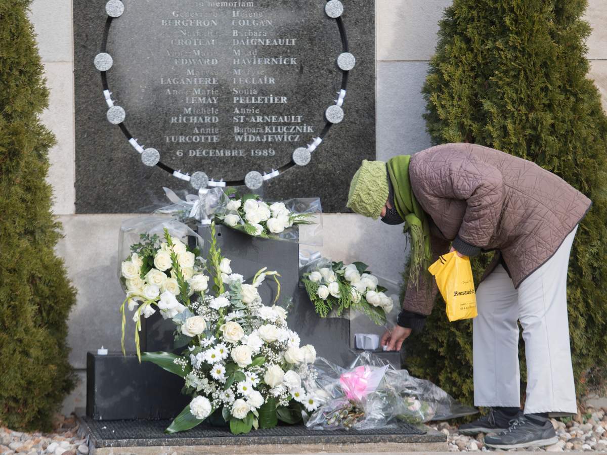 Marie Bolduc places candles on the commemorative plaque on the wall of Polytechnique in Montreal, Sunday, Dec. 6, 2020, on the 31st anniversary of the murder of 14 women in an anti-feminist attack at École Polytechnique on December 6, 1989. The COVID-19 pandemic continues in Canada and around the world. 