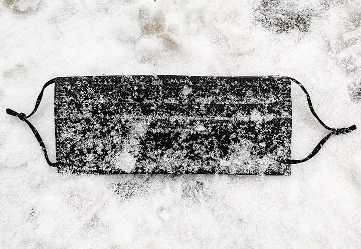 A discarded black face mask is shown on a street following snowfall in Montreal, Wednesday, Dec. 9, 2020, as the COVID-19 pandemic continues in Canada and around the world. 