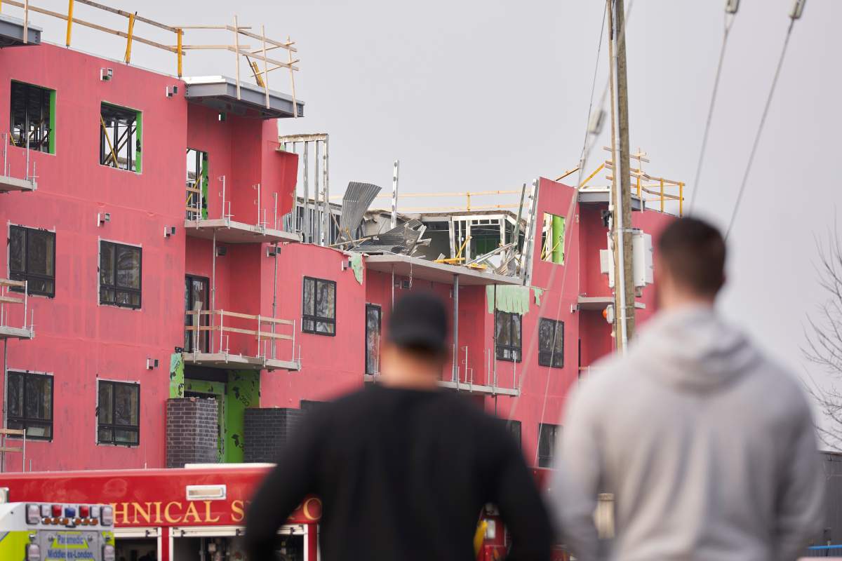 Two blurry people in the foreground in front of a building under construction in the background.