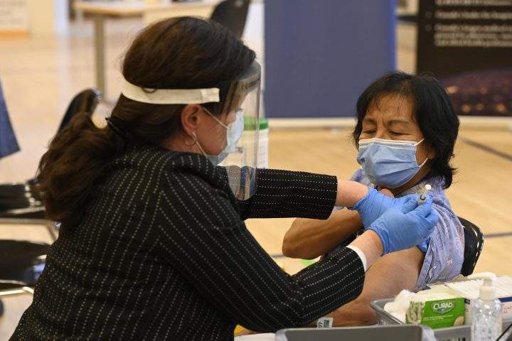 Tamara Dus (left), director of University Health Netwok Safety Services, administers the first Pfizer-BioNTech COVID-19 vaccine in Ontario to personal support worker Anita Quidangen at a hospital in Toronto on Monday, Dec. 14, 2020.