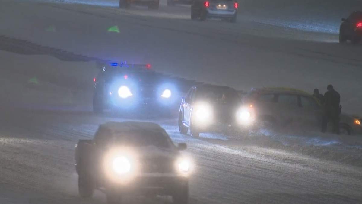Emergency crews are seen tending to a car in the ditch in Calgary amid heavy snow on Dec. 22, 2020.