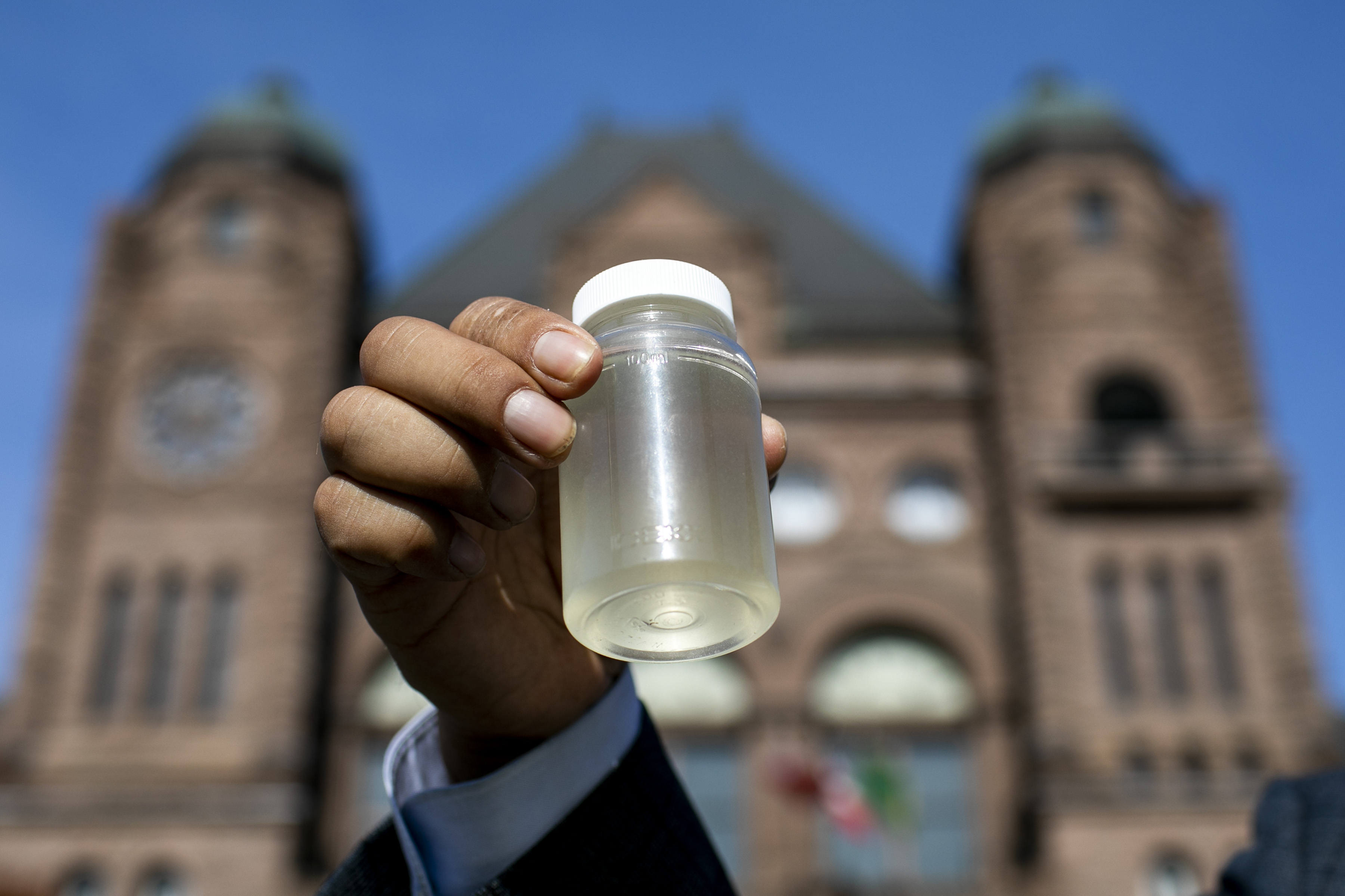 Kiiwetinoong MPP Sol Mamakwa holds up water collected from Neskantaga First Nation,  where residents were evacuated over tainted water last month, during a rally at Queen's Park in Toronto on Friday, Nov.6, 2020.