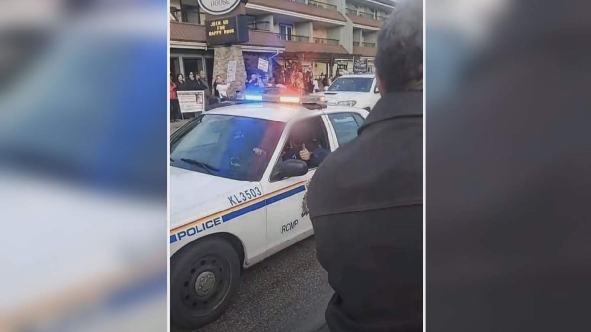 A Kelowna Mountie gives a thumbs up in an exchange with protesters about where they can stand on the sidewalk.