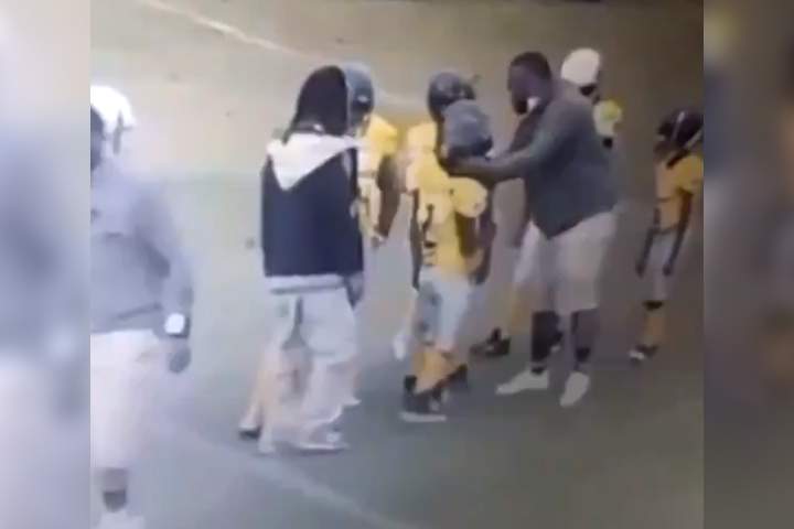 A Savannah Gators youth coach, right, holds a player by the helmet on the field at a game in Kissimmee, Fla., in this image from video recorded Dec. 7, 2020.