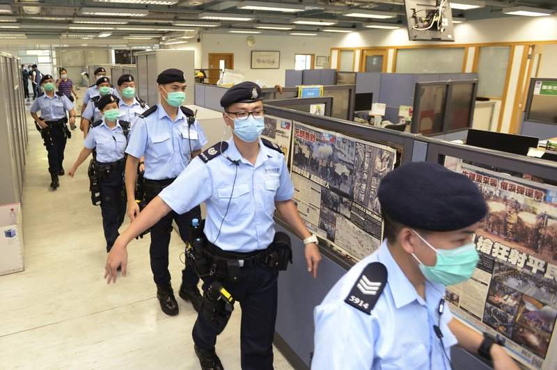 In this Monday, Aug. 10, 2020, photo, police officers take enter the Apple Daily newspaper headquarters as founder Jimmy Lai is arrested by police officers at his home in Hong Kong. Seven human rights experts affiliated with the U.N. raised concerns over Hong Kong's national security law in a letter addressed to Chinese authorities, saying that the law infringed on certain fundamental rights. 