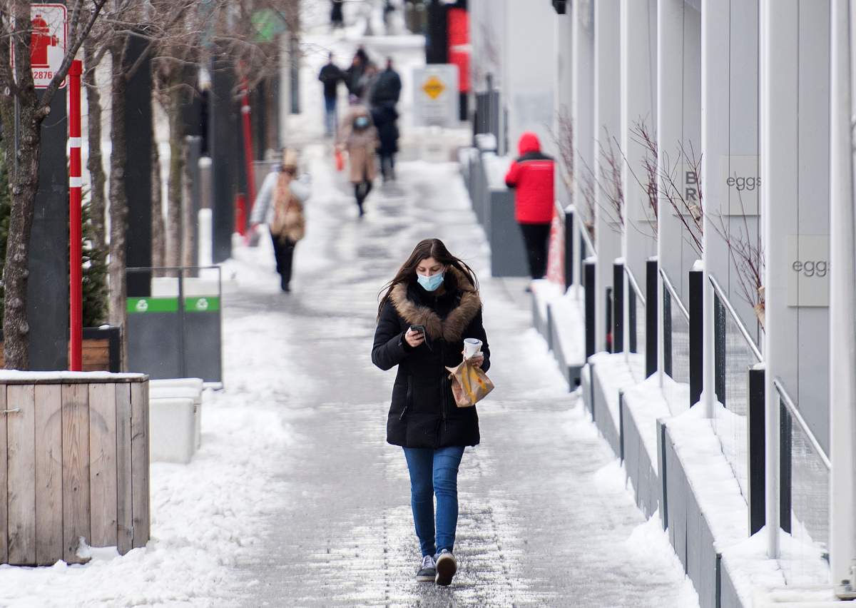 A woman wears a face mask as she walks along a street in Montreal, Thursday, December 31, 2020. 
