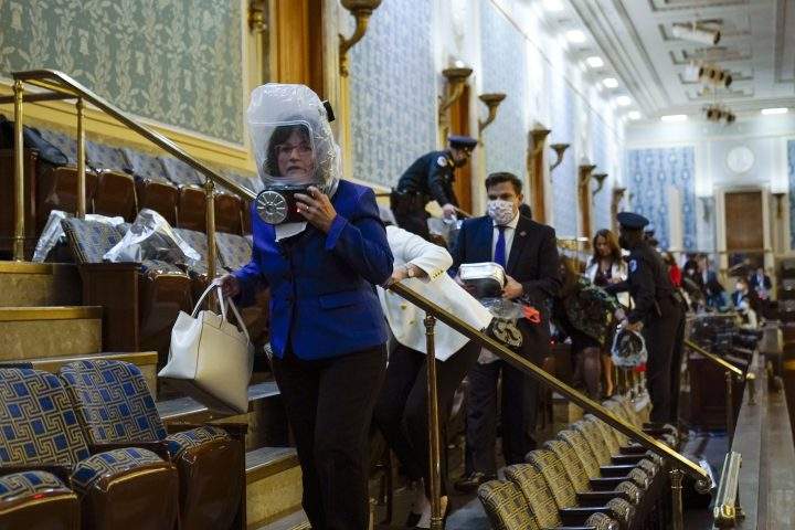 People shelter in the House gallery as protesters try to break into the House Chamber at the U.S. Capitol on Wednesday, Jan. 6, 2021, in Washington.