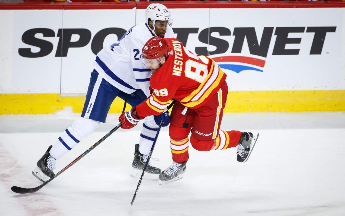 Toronto Maple Leafs’ Wayne Simmonds, left, is checked by Calgary Flames’ Nikita Nesterov during first period NHL hockey action in Calgary, Tuesday, Jan. 26, 2021.