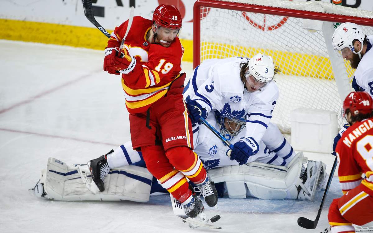 Toronto Maple Leafs’ Justin Holl, right, crashes over goalie Frederik Andersen, centre, trying keep Calgary Flames’ Matthew Tkachuk from the puck during second period NHL hockey action in Calgary, Tuesday, Jan. 26, 2021.