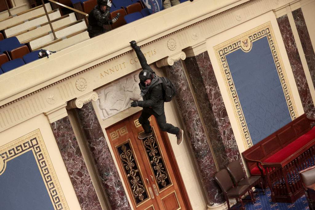 A protester is seen hanging from the balcony in the Senate Chamber on January 06, 2021 in Washington, D.C.