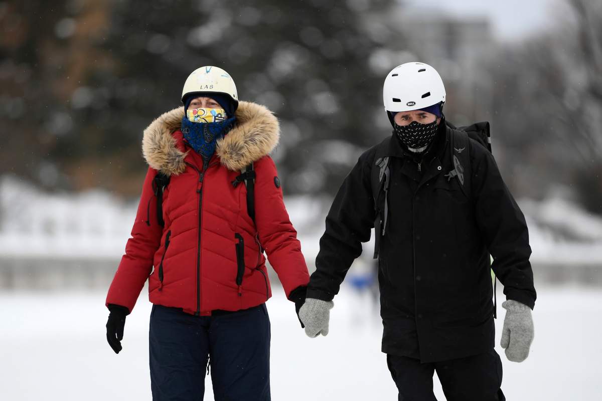 People wear masks as they make their way along the Rideau Canal Skateway on its opening day in Ottawa, on Thursday, Jan. 28, 2021, in the midst of the COVID-19 pandemic. The Rideau Canal is a UNESCO World Heritage Site. 