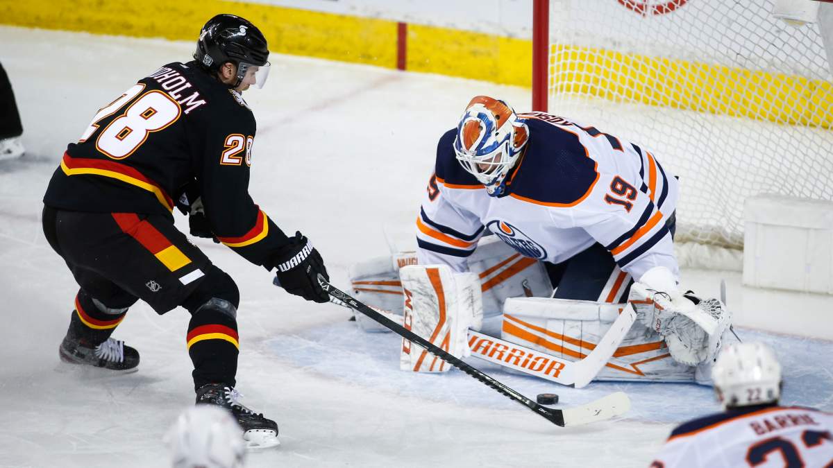 Edmonton Oilers goalie Mikko Koskinen, right, stops Calgary Flames' Elias Lindholm during second period NHL hockey action in Calgary, Saturday, Feb. 6, 2021.THE CANADIAN PRESS/Jeff McIntosh.