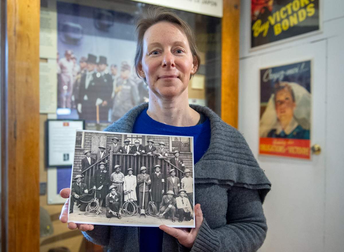 Chara Kingston, collections manager at The Army Museum at the Halifax Citadel National Historic Site, displays a photo of an all-Black fire brigade on Thursday, Feb. 25, 2021. The civilian fire wardens were part of the Air-Raid Precautions Group, which was formed by the federal government in 1939 and disbanded in 1945.