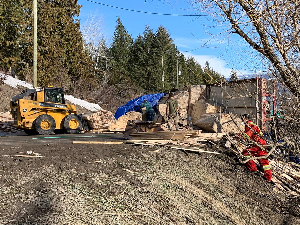 Work crews cleaning up the spilled lumber along Highway 97A.