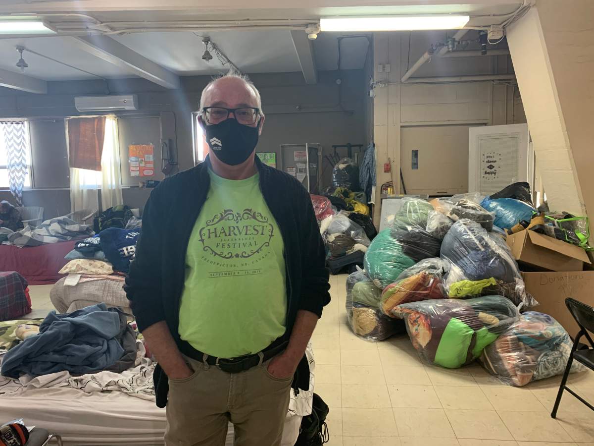 Warren Maddox inside St. John House in Fredericton in front of a coat drive donation.