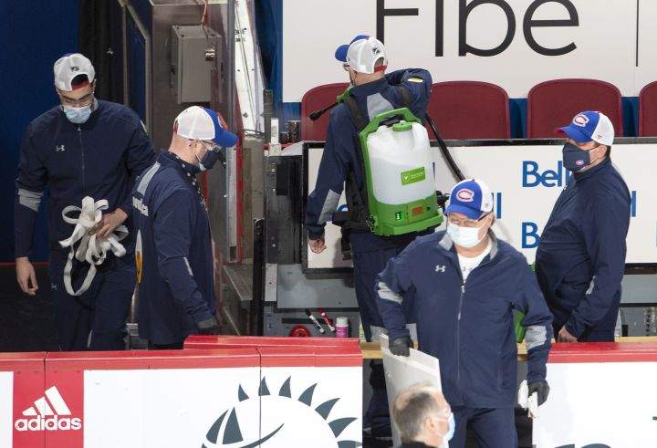 Arena workers clean the player's bench before NHL hockey action between the Edmonton Oilers and Montreal Canadiens, in Montreal, Thursday, Feb. 11, 2021. The game has been delayed by an hour after an Oilers player was placed on the league's COVID-19 protocol. 