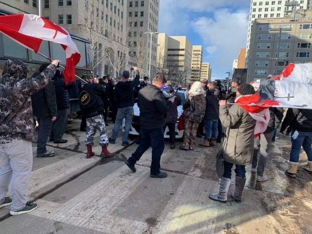 Protesters surround a police vehicle near the Alberta legislature in Edmonton on Saturday, Feb. 20, 2021.