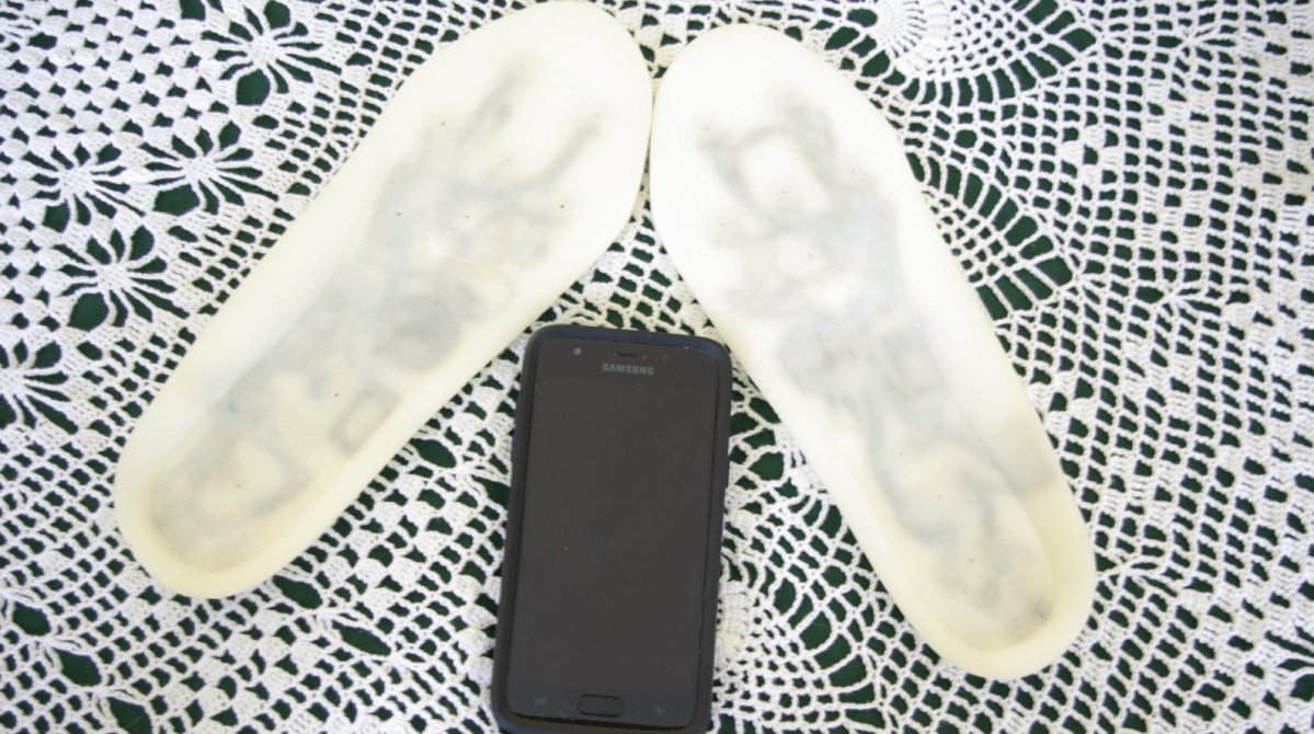 A pair of bluetooth-capable ‘Smart Shoes’ displayed next to a phone.