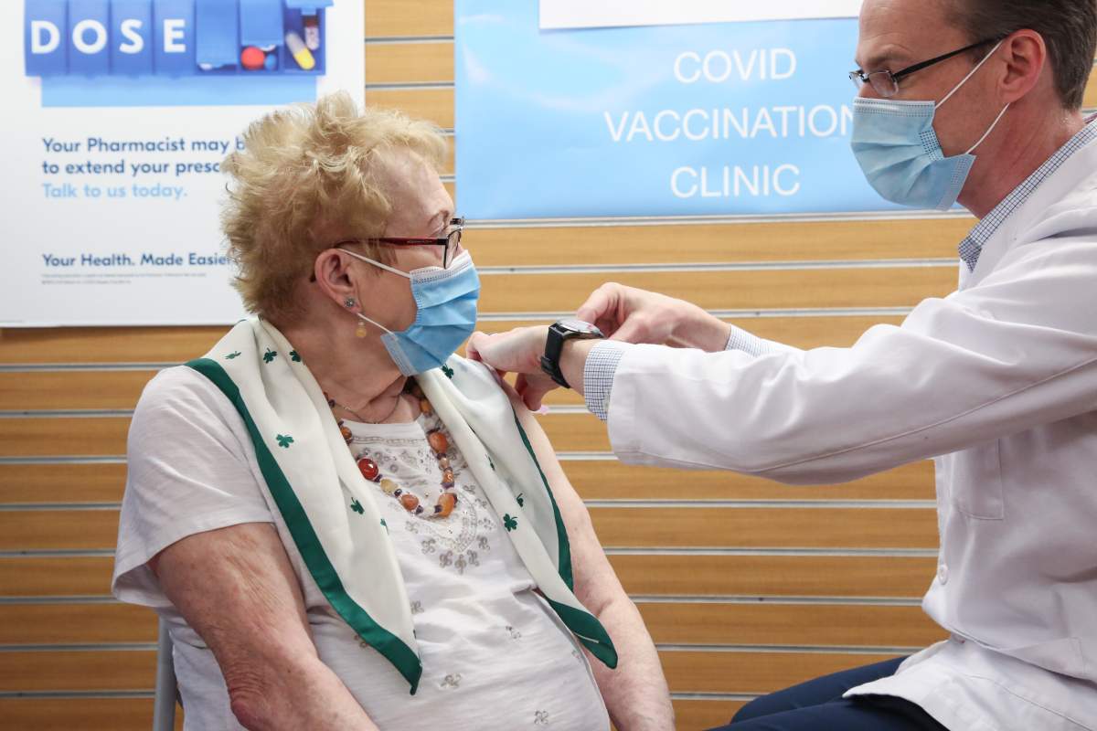 Pharmacist Ryan Quinn administers a vaccine to Corrie Hudson, 88, the first New Brunswicker over 85 to receive the COVID-19 vaccine from a pharmacist.