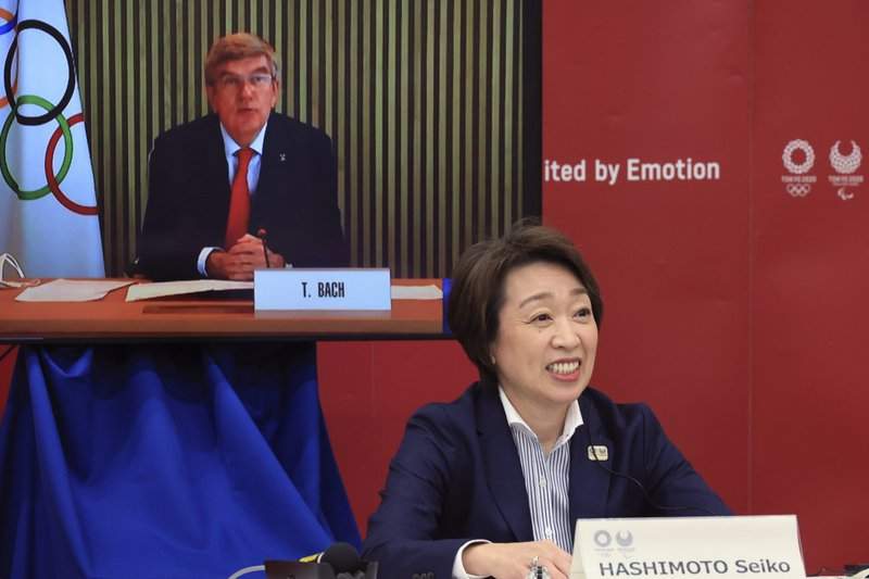 International Olympic Committee (IOC) President Thomas Bach, on a screen, delivers an opening speech while Tokyo 2020 Organizing Committee President Seiko Hashimoto listens at a five-party meeting of Tokyo 2020 Olympic and Paralympic Games with International Paralympic Committee (IPC) President Andrew Parsons, Tokyo Gov. Yuriko Koike and Japanese Olympic Minister Tamayo Marukawa in Tokyo Saturday, March 20, 2021.