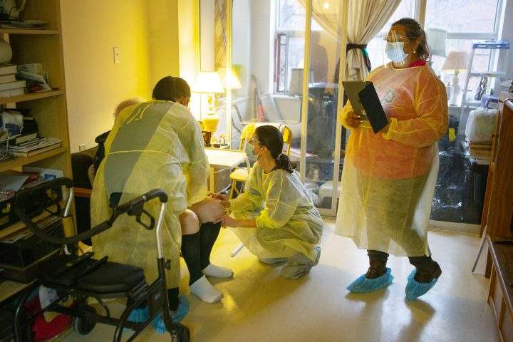 Personal Support Workers dressed in personal protective equipment (PPE) tend to a client at Toronto's  Springhurst Manor on Friday December 4, 2020.