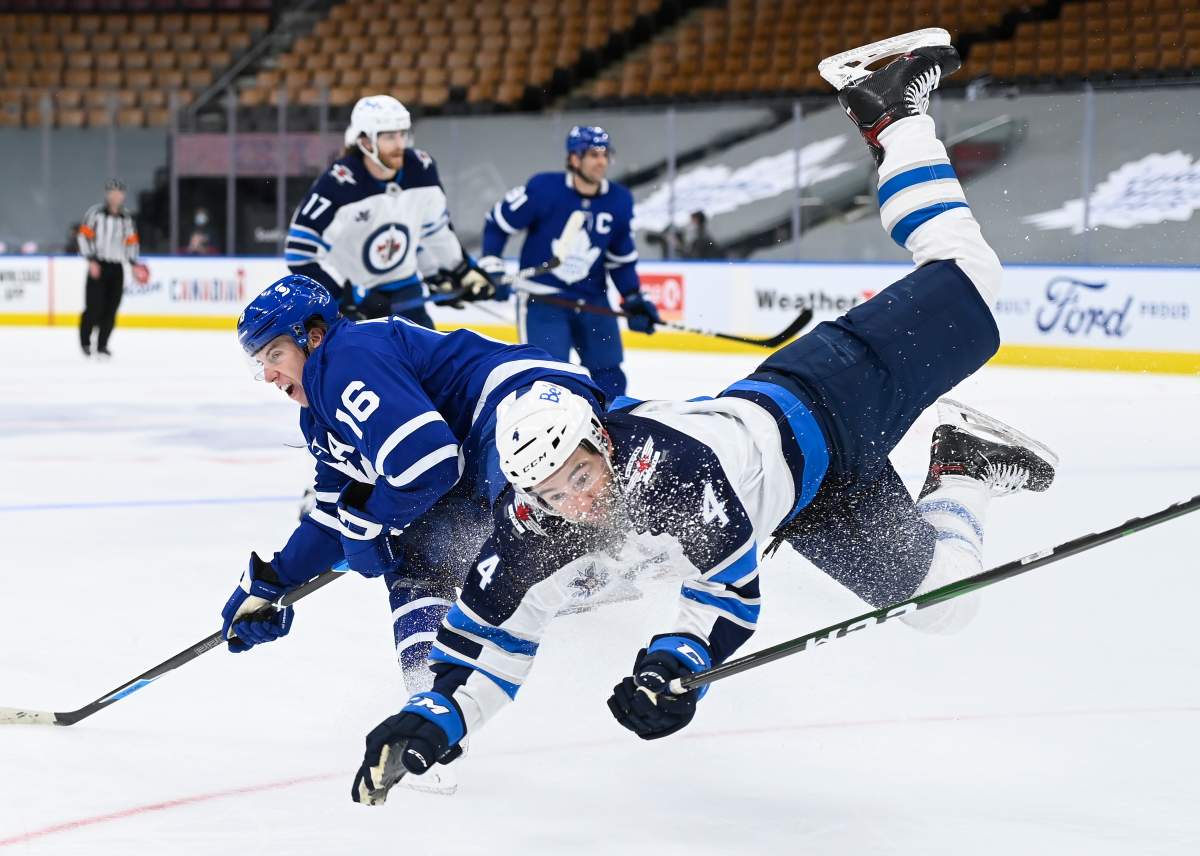 Toronto Maple Leafs right wing Mitchell Marner (16) scores on an empty net and take a hit from Winnipeg Jets defenceman Neal Pionk (4) during third-period NHL hockey action in Toronto on Monday, Jan. 18, 2021.