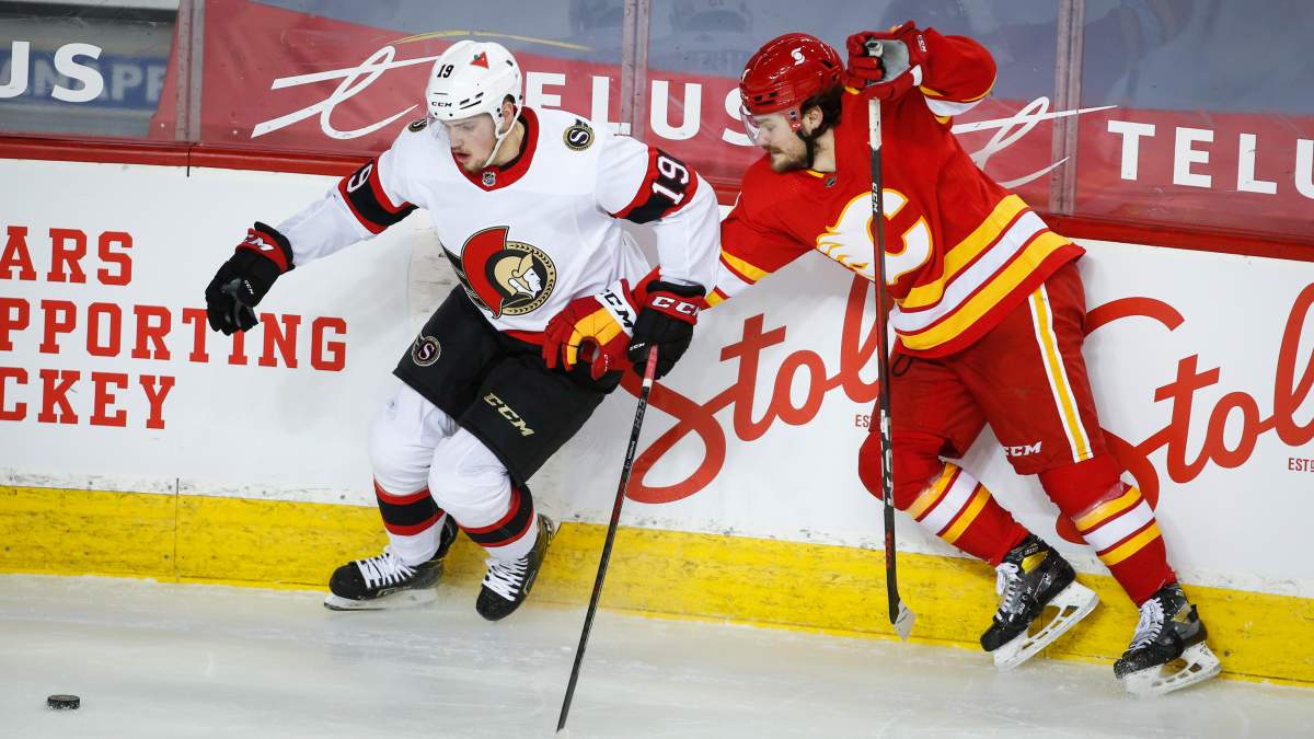 Ottawa Senators' Drake Batherson, left, and Calgary Flames' Rasmus Andersson chase the puck during second period NHL hockey action in Calgary, Sunday, March 7, 2021.